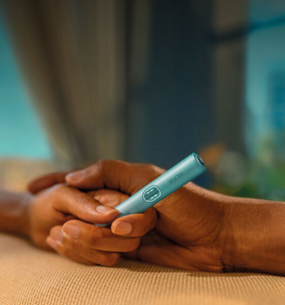 An IQOS ILUMA Pocket Charger and Holder on a laptop.