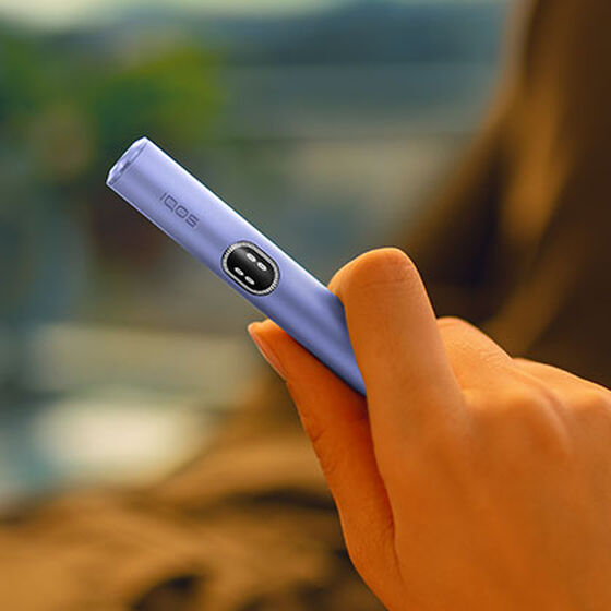 A person placing an IQOS ILUMA Pocket Charger into a charging station.