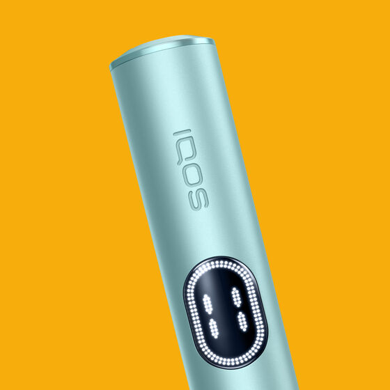 Close up of woman taking jade green IQOS ILUMA Prime device from holder.