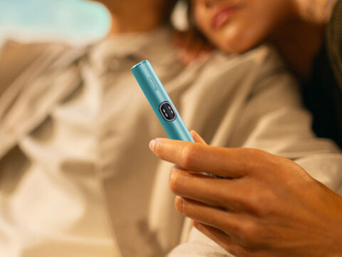 A person holding an unopened IQOS device box.