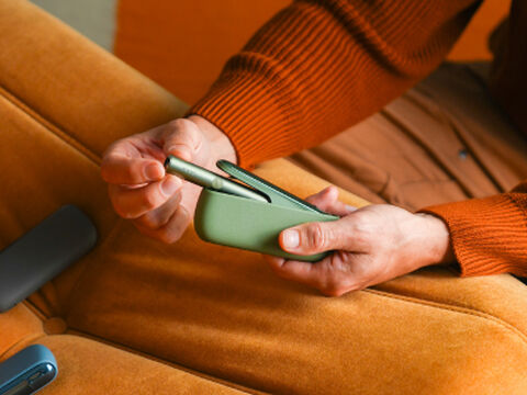 Hands holding smartphones and one IQOS device.