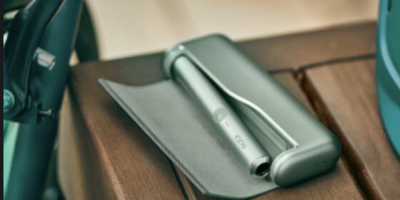 A Jade Green IQOS ILUMA PRIME Holder and Pocket Charger in a person's hands.