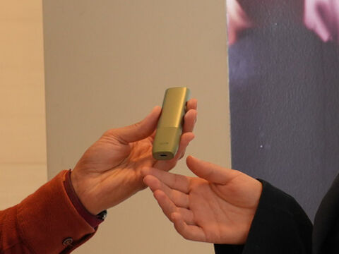 A person holding an unopened IQOS device box.