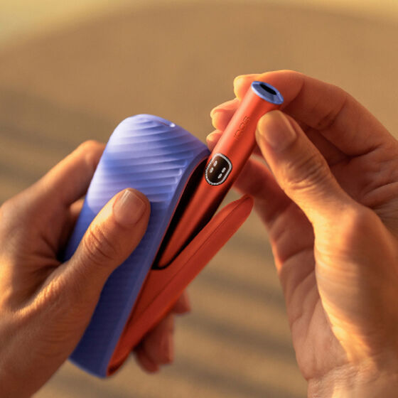 A charging cable being inserted into an IQOS ILUMA Holder.