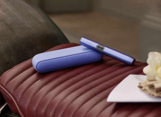 Koyu merdivenli arka plan - IQOS cihazı tutan eller - IQOS logosuyla birlikte