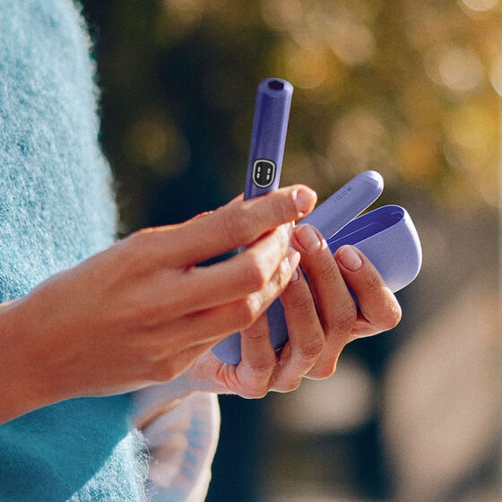 A charging cable being inserted into an IQOS ILUMA Holder.