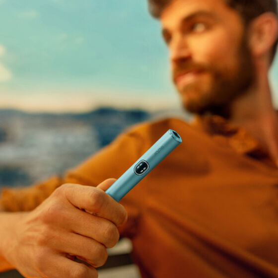 A person holding an IQOS ILUMA Pocket Charger and Holder. 