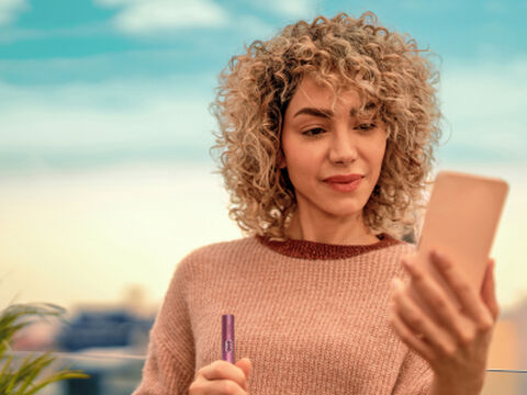 Hands holding an unopened IQOS device box.