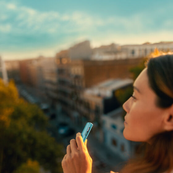 A person placing an IQOS ILUMA Pocket Charger into a charging station.