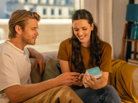 Hands holding smartphones and one IQOS device.