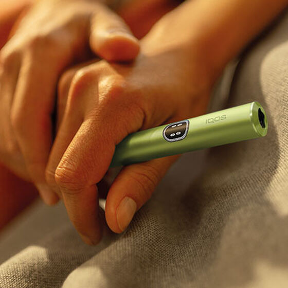 A person holding an IQOS ILUMA Pocket Charger and Holder. 
