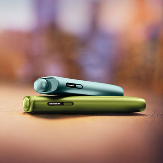 A moss green IQOS ILUMA Holder inside a Pocket Charger.