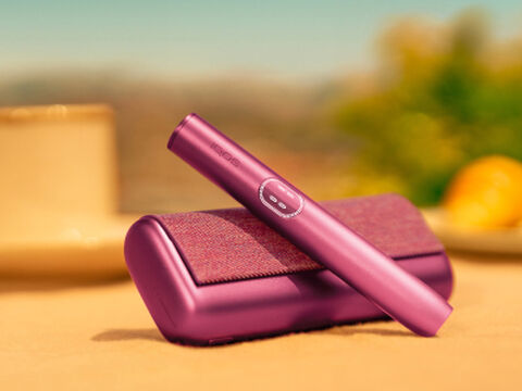 A person holding an unopened IQOS device box.